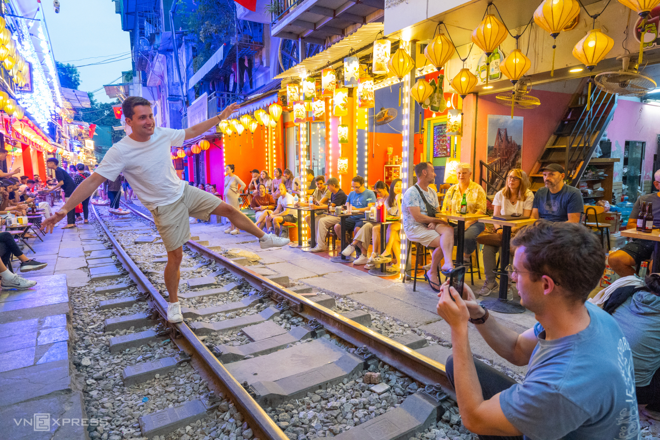 A train approaching visitors seated along Hanoi Train Street